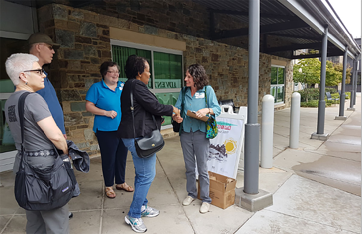 Tour leader Clare Lise Kelly (right) of the Montgomery County Planning Department greets Tina Patterson, the newest Planning Board member, who joined the group on the bus.