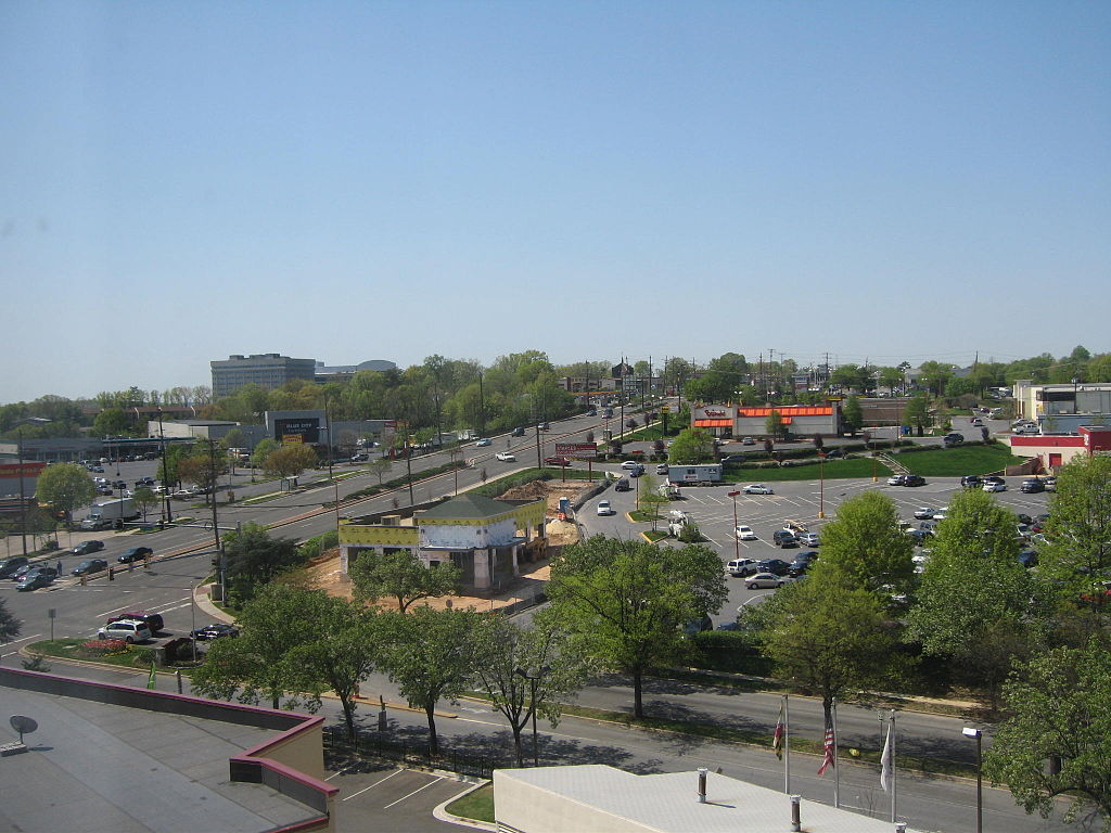 a large parking lot with some buildings in the background at the New Carrollton Metro Station in Prince George’s County. A scattering of cars are parked in the parking lot