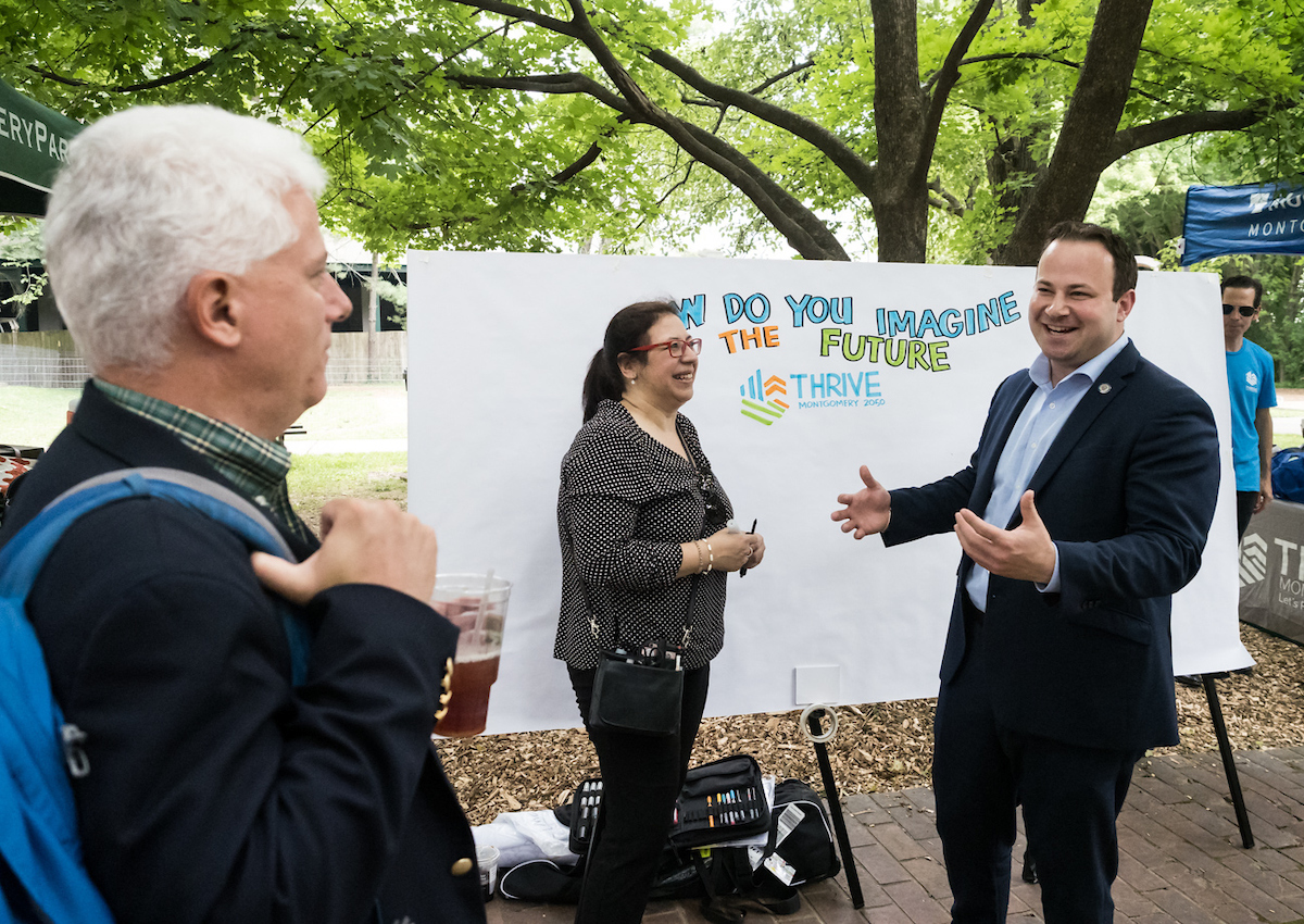 Planning Board Chair Casey Anderson and Montgomery County Councilman Andrew Friedson talk with graphic recording artist at Yappy Hour