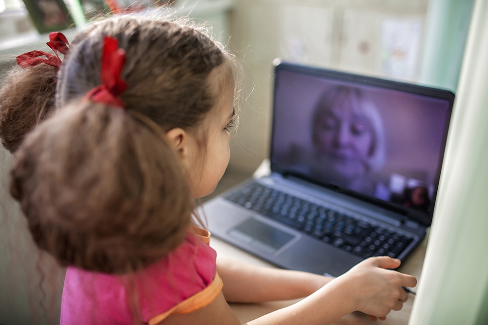 Cute girl talking with her grandmother within video chat on laptop, digital conversation, life in quarantine time, self-isolation