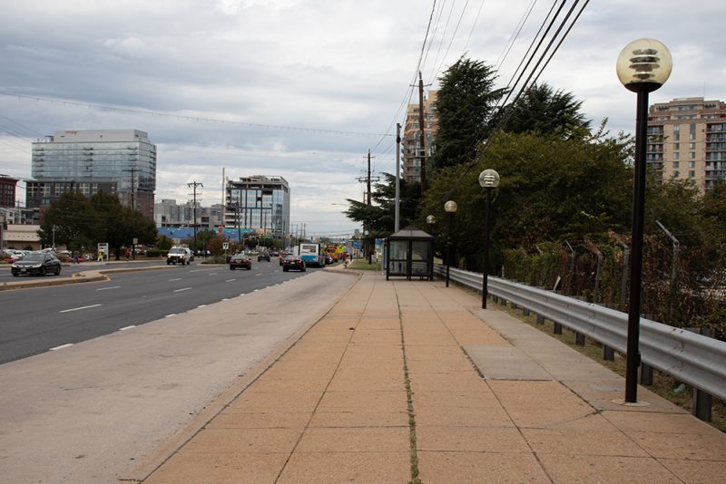 a road with traffic on the left and sidewalks on the right showing an unattractive corridor.