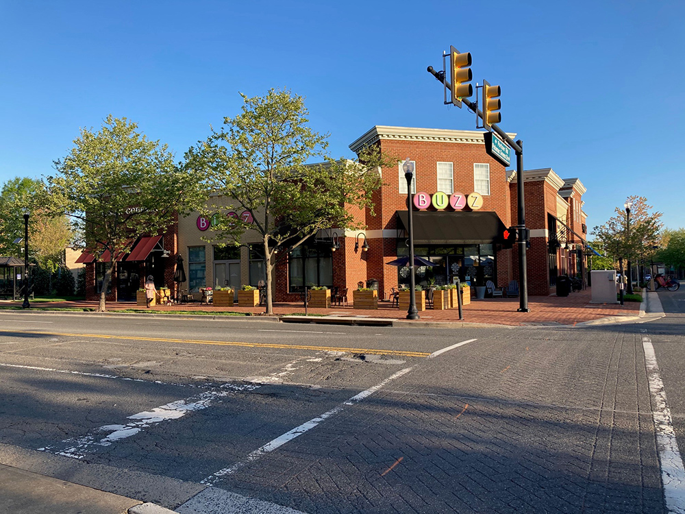 corner of a neighborhood main street with retail on the ground floor in brick buildings with wide sidewalks