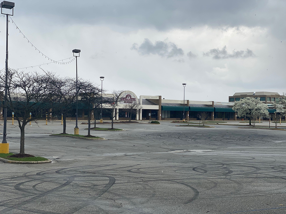 urtonsville Crossing shopping center in Burtonsville, MD. Shows empty parking lot, and empty store fronts with tire marks on the pavement.