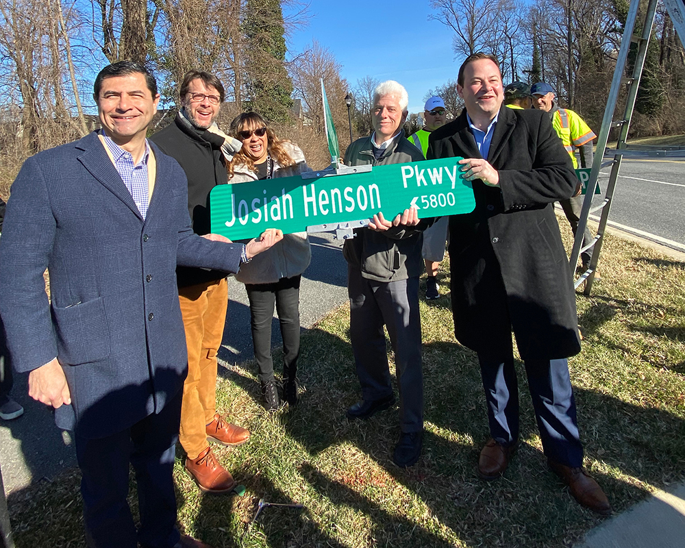 From left, Montgomery County Council President Gabe Albornoz, Councilmember Hans Riemer, Angela Brown, Montgomery Planning Intake and Regulatory Coordination Manager, Montgomery County Planning Board Chair Casey Anderson, and Councilmember Andrew Friedman hold the new Josiah Henson Parkway sign shortly before it is installed. 