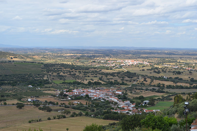 aerial view of Monsaraz, Portugal showing dense towns surrounded by green fields.