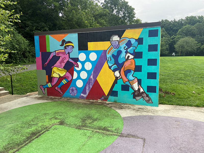 Bright colored mural featuring a soccer player and an ice hockey player at Dewey Local Park