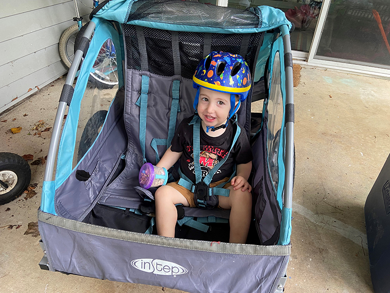 Toddler wearing a bike helmet in a bike trailer