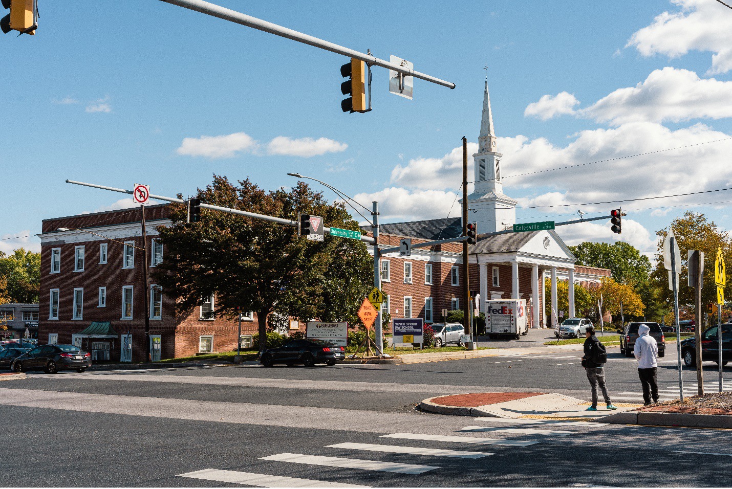 large red brick church with tall white steeple at multilane intersection