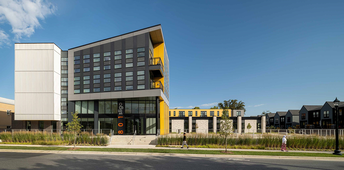Modern yellow and gray multistory building with large windows on all floors