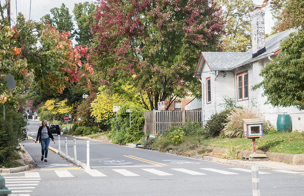 A woman walking down a suburban street in a dedicated pedestrian lane.