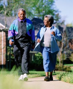 two senior adults walking on a sidewalk