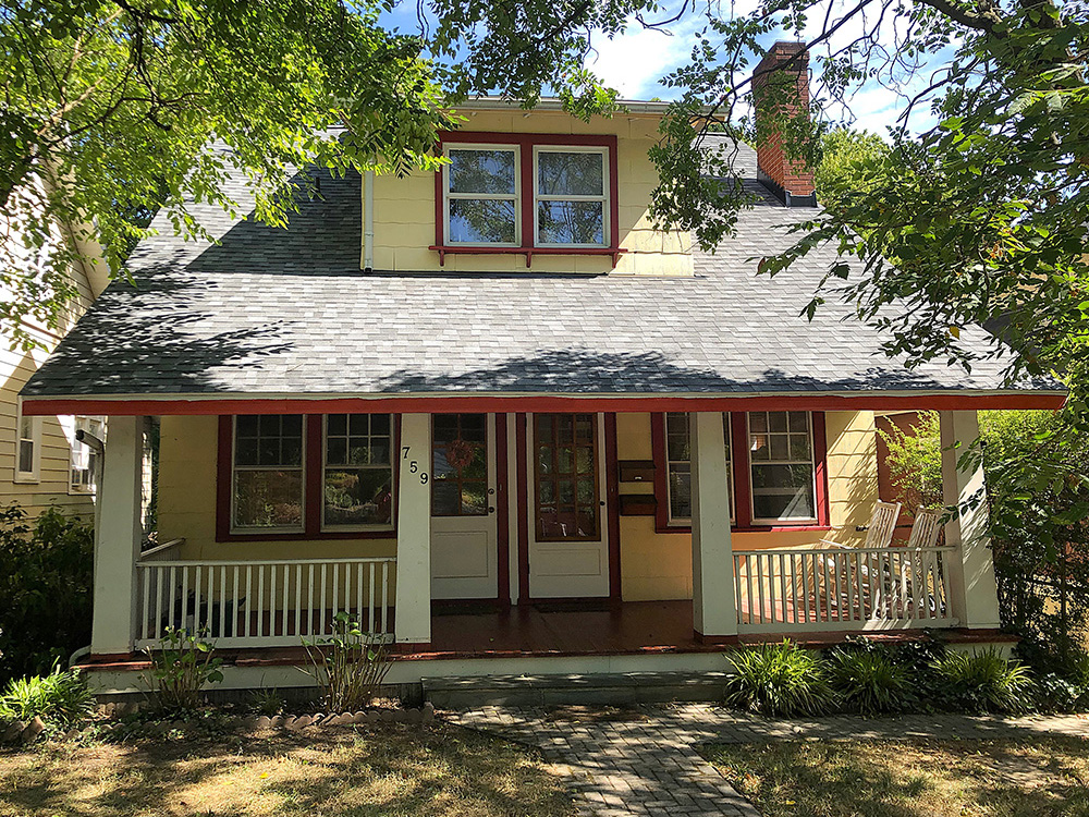 two story yellow house with red trim and two front doors