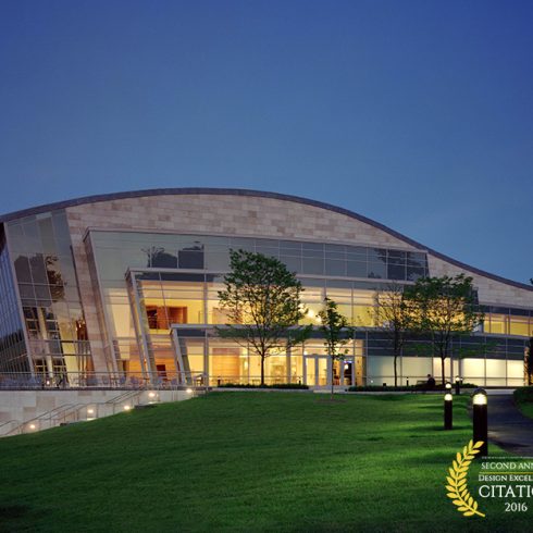 building lit up in evening with large windows at curved roof