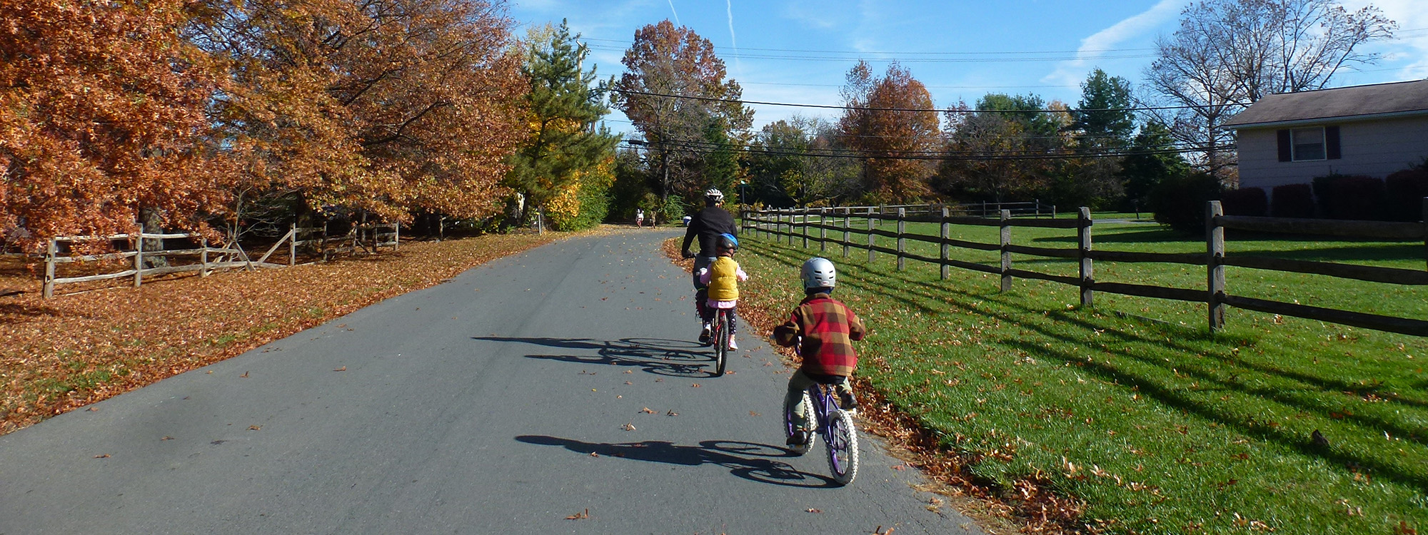 family riding bikes on rural road in autumn