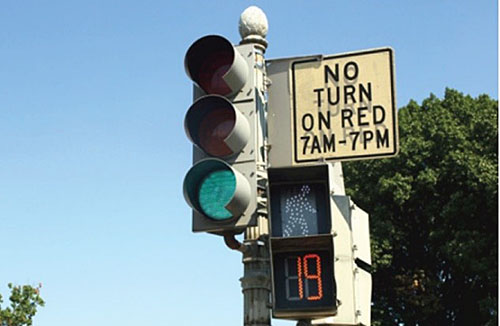 A sign next to a traffic signal indicates that no vehicles may turn right on a red signal between 7 a.m. and 7 p.m.