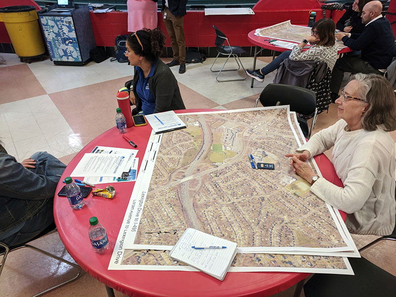 community members sit at table with large area map, index cards, and markers at in-person workshop