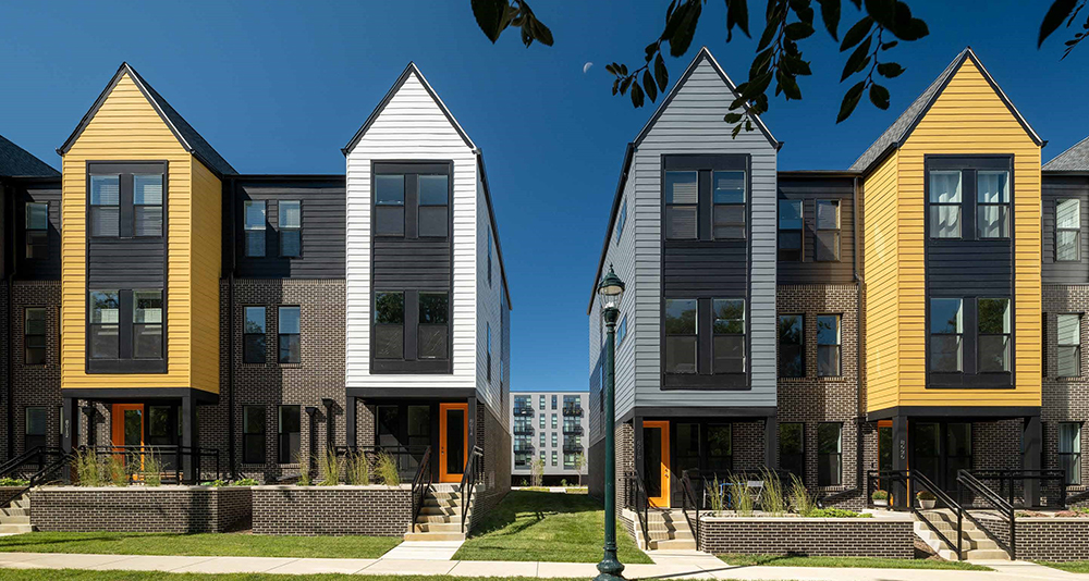 four gray brick town homes each with yellow, white of gray siding on portion of structure