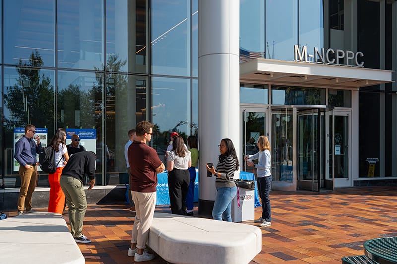 People talking in groups in front of M-NCPPC Wheaton HQ