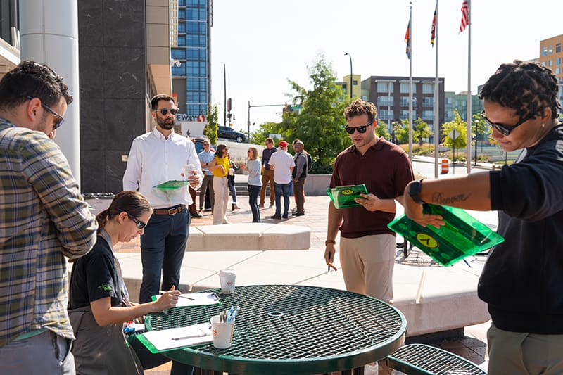 People holding and looking at clipboards around a round picnic table