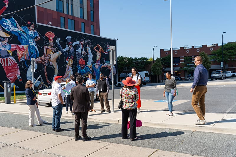 People talking in group next to mural of people dancing