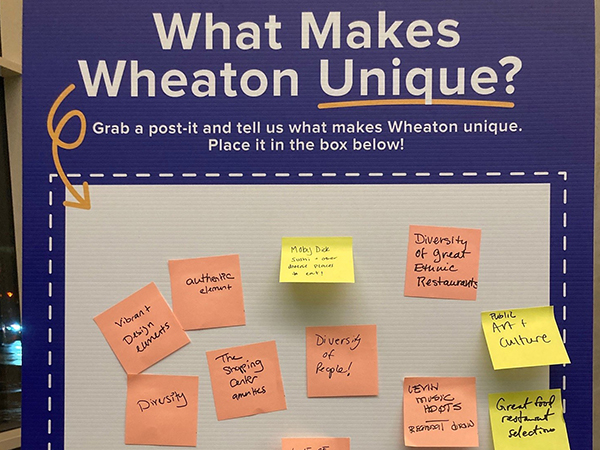 Bulletin board titled "What Makes Wheaton Unique?" with various sticky notes listing diversity, art culture, restaurants, and other local qualities.