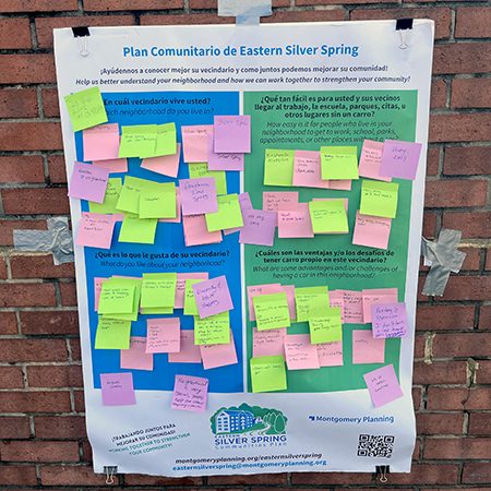 A community planning poster with colorful sticky notes displaying feedback in Spanish and English on improving Eastern Silver Spring.