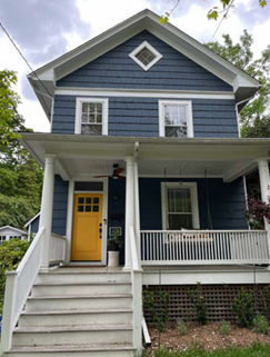 A two-story blue house with a porch and yellow door.